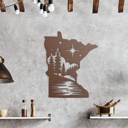 A metal wall art piece shaped like the state of Minnesota, featuring a cutout landscape design with trees, stars, and a river, displayed on a gray concrete kitchen wall above a wooden countertop.