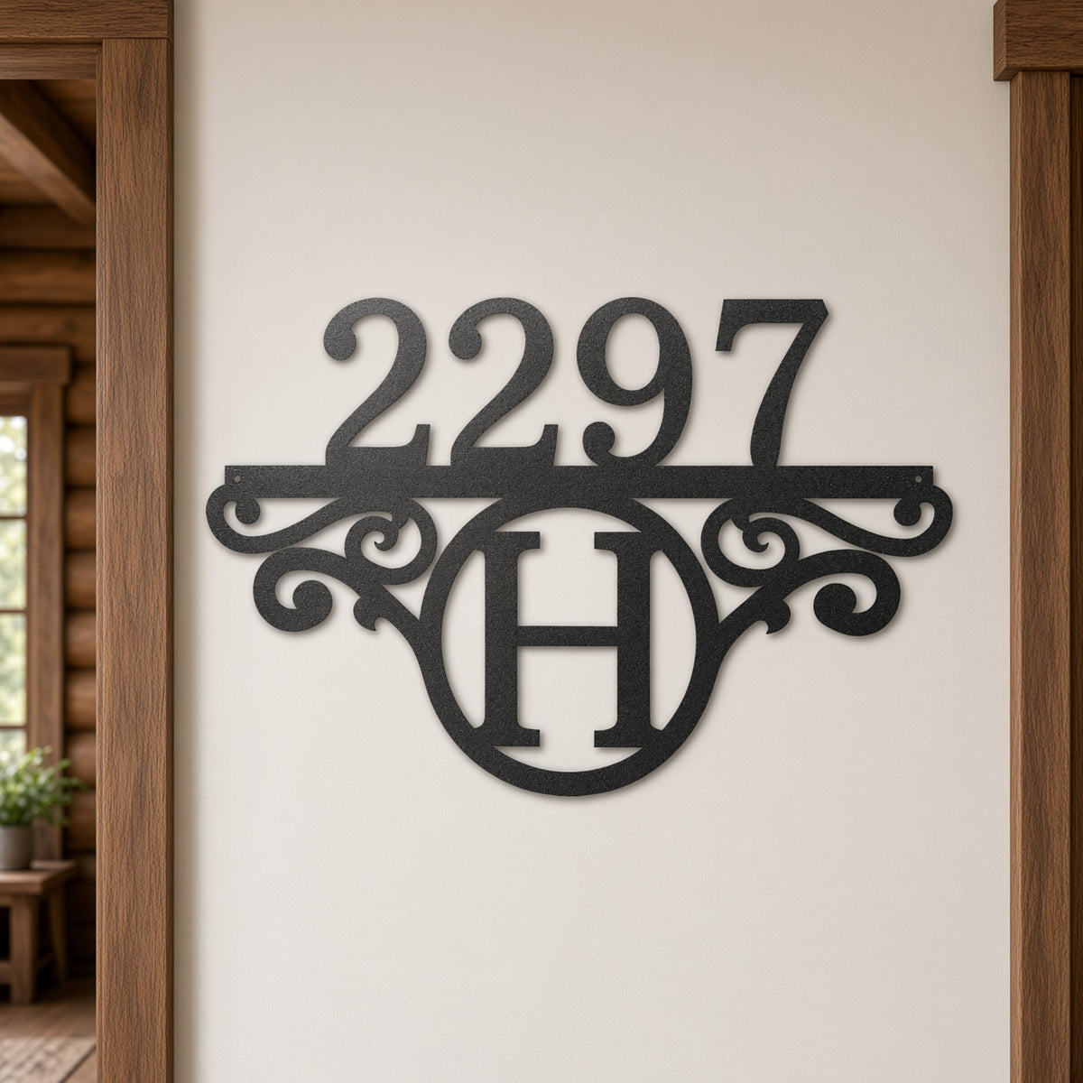 Black metal house number and monogram wall decor reading 2297 with an ornate scroll design and circular H monogram, mounted on a beige wall in a rustic wood doorway.