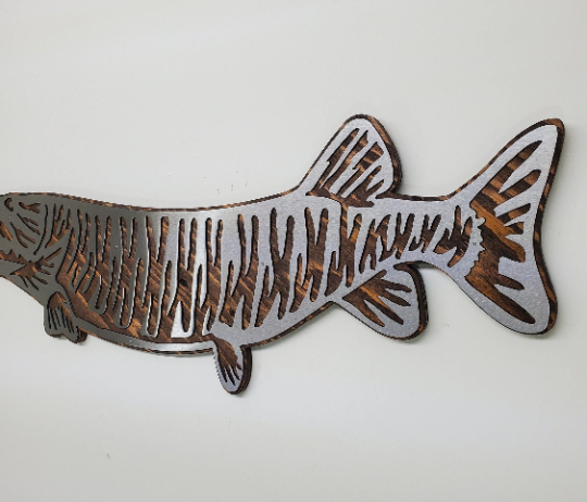 This Muskie fish sculpture art is a beautiful and unique wall decor piece, featuring an artistic representation of the elusive and challenging king catch - the Muskie. It is made using rustic stained wood and clear-coated steel