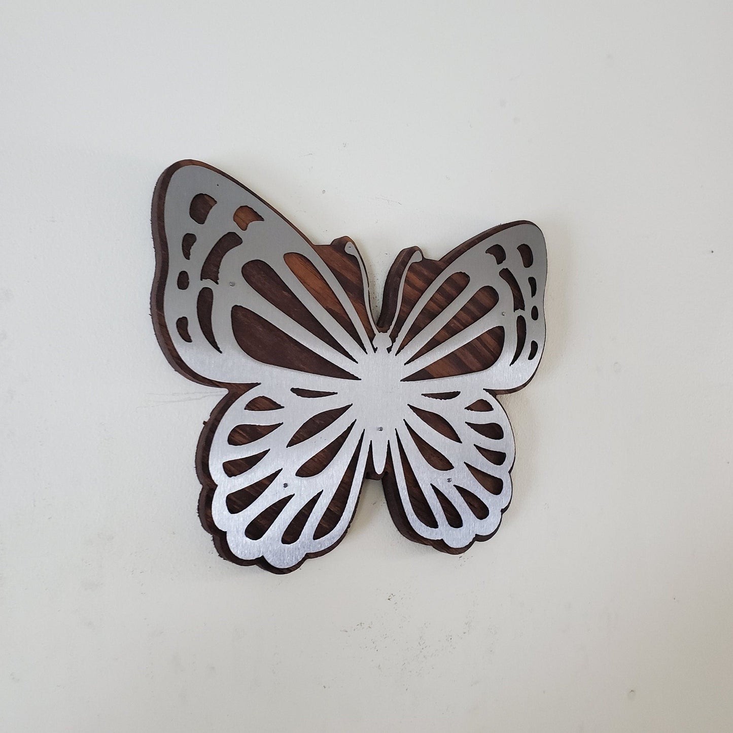 Metal Art wall decor Butterfly to highlight the beautiful wood grains through delicate steel cutout details which seem to frame the rustic wood beneath it. The metal reflects light, mimicking the sun’s rays