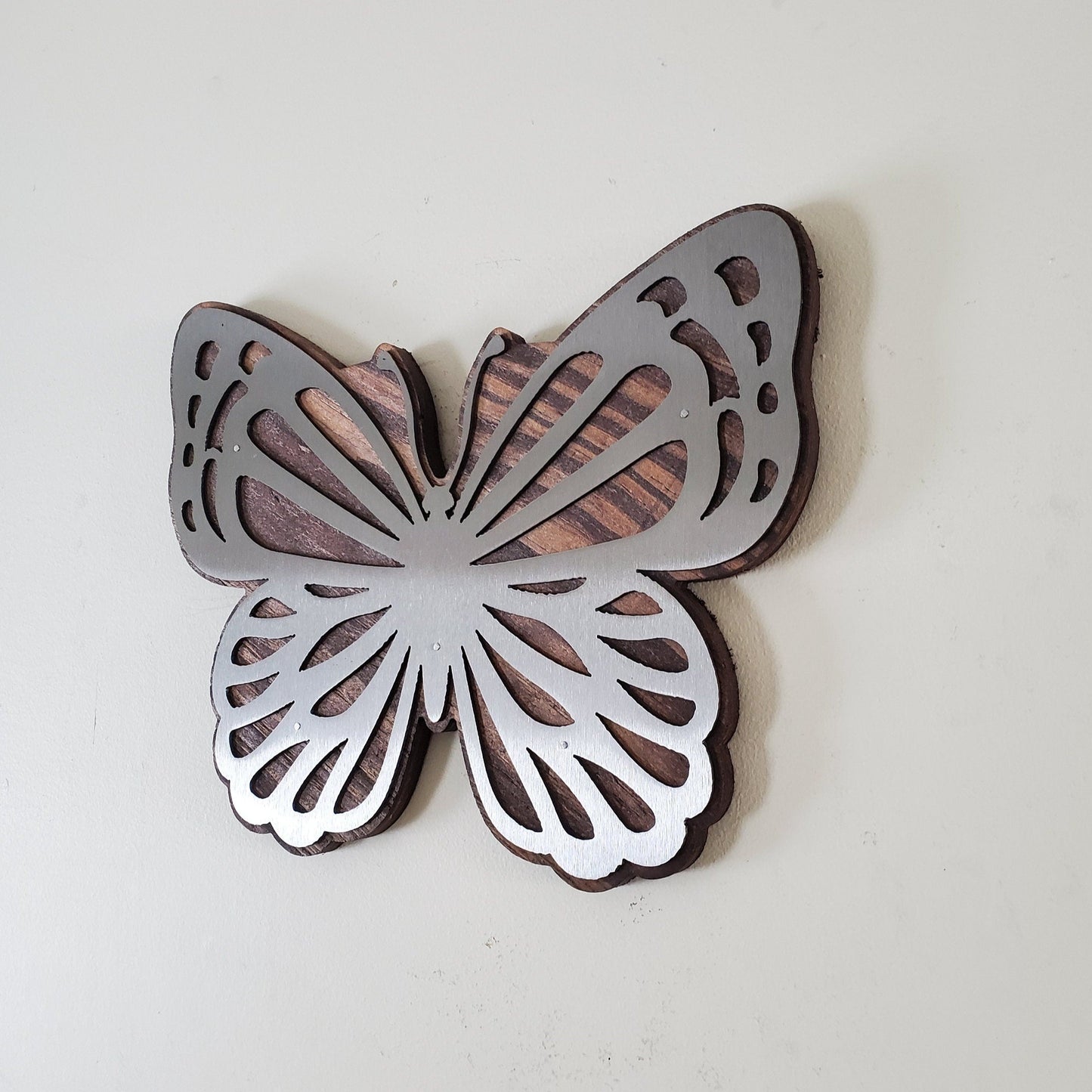 Metal Art wall decor Butterfly to highlight the beautiful wood grains through delicate steel cutout details which seem to frame the rustic wood beneath it. The metal reflects light, mimicking the sun’s rays