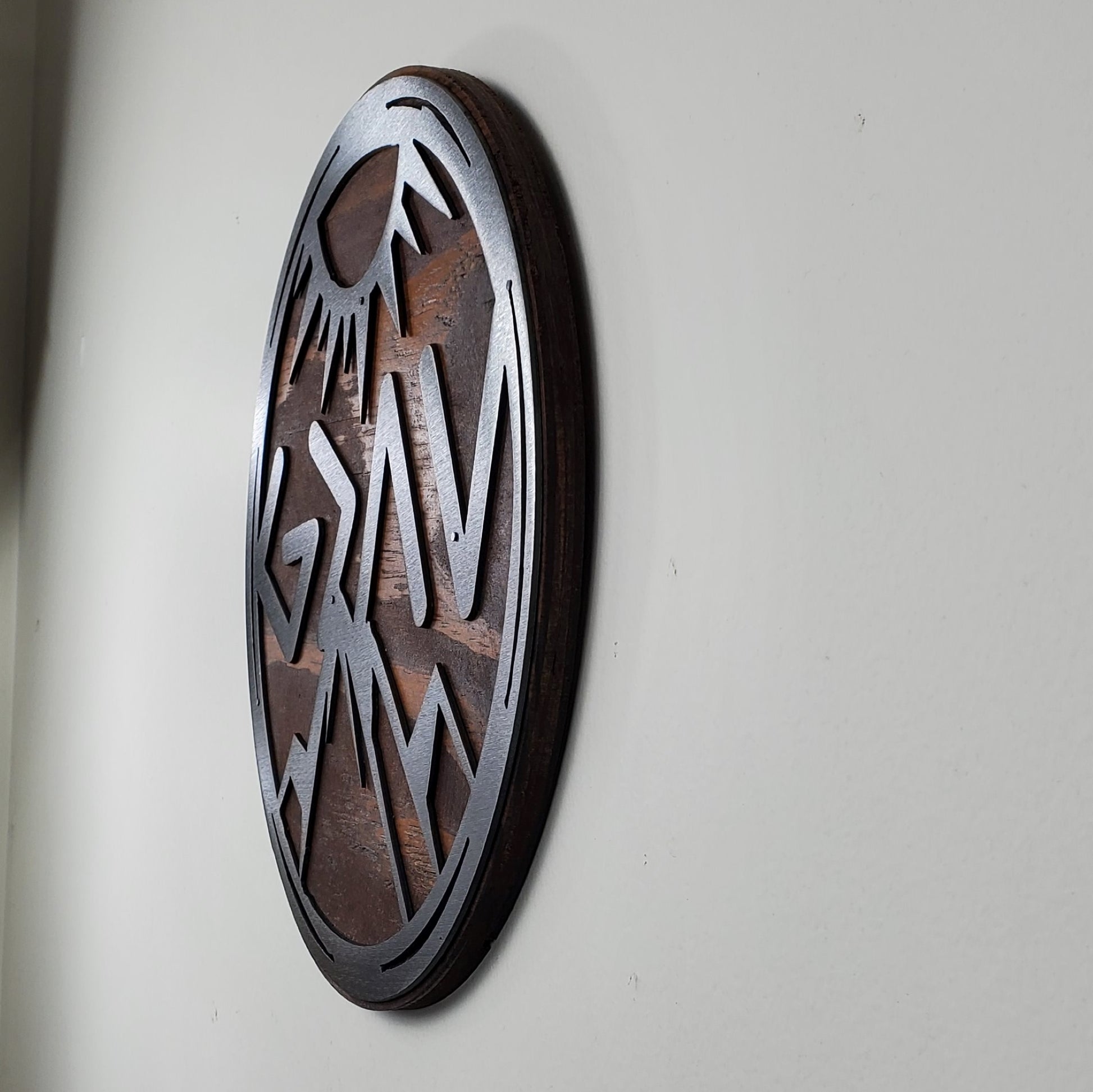 God is Greater Than the Highs and Lows Greek letters and mountains  metal art on stained wood circle design