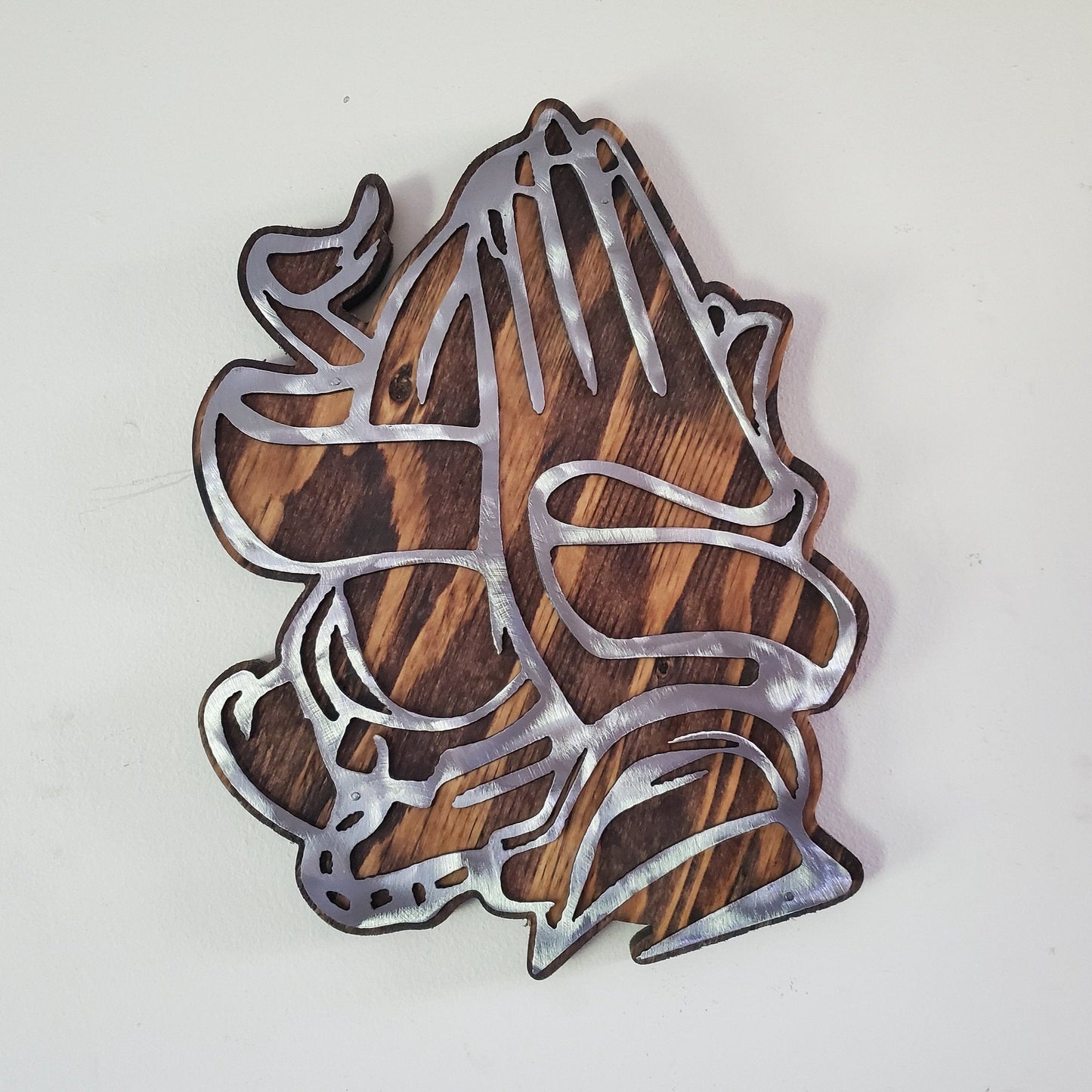 The Praying Hands showing of Faith metal art on wood wall décor is the perfect way to show your appreciation for the spiritual side in your life. This unique piece of art is finished by hand