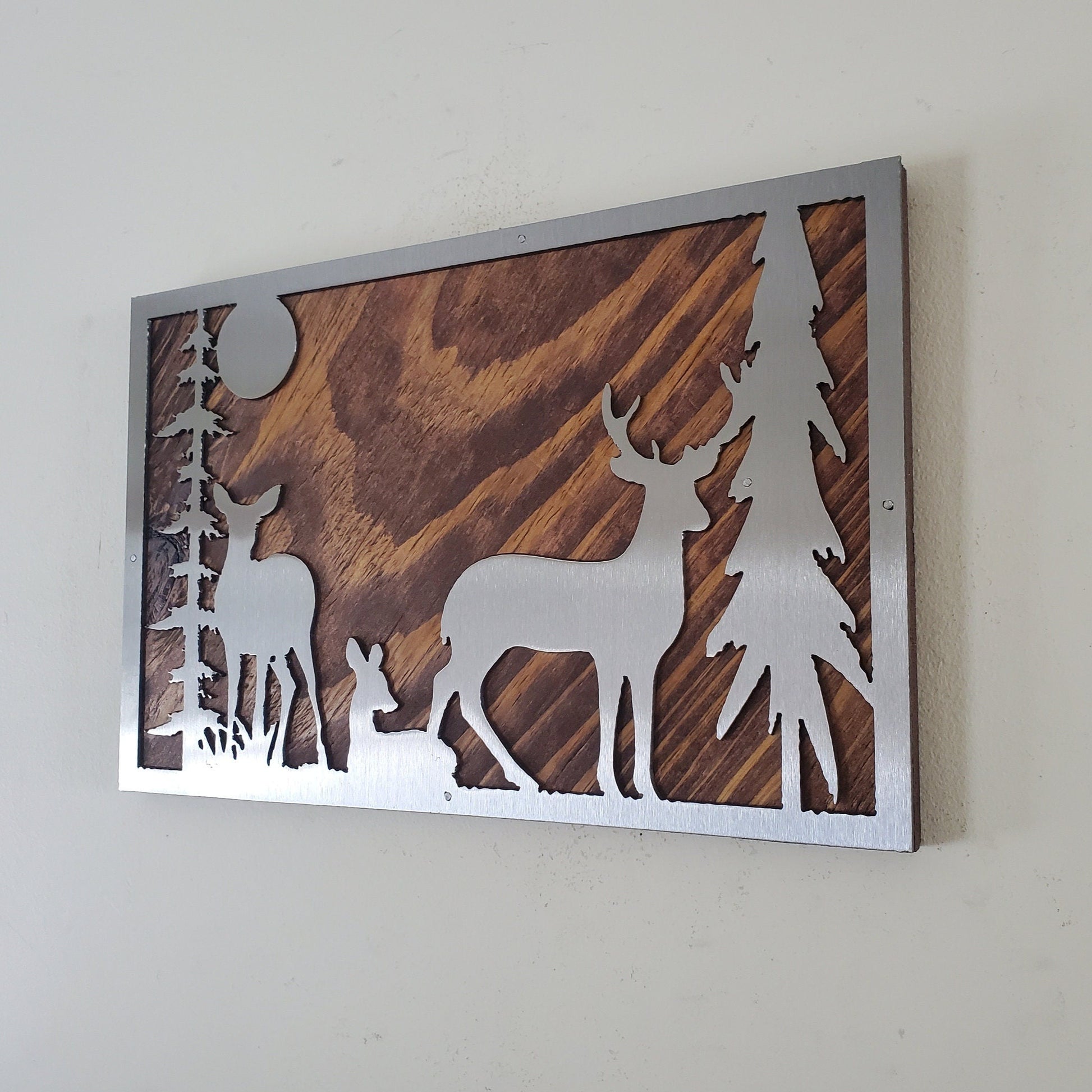 Metal art wall decor featuring a detailed and textured depiction of a deer in the woods, made of clear coated steel with rustic wood back.  A striking and unique piece, ideal for nature and outdoor enthusiasts.