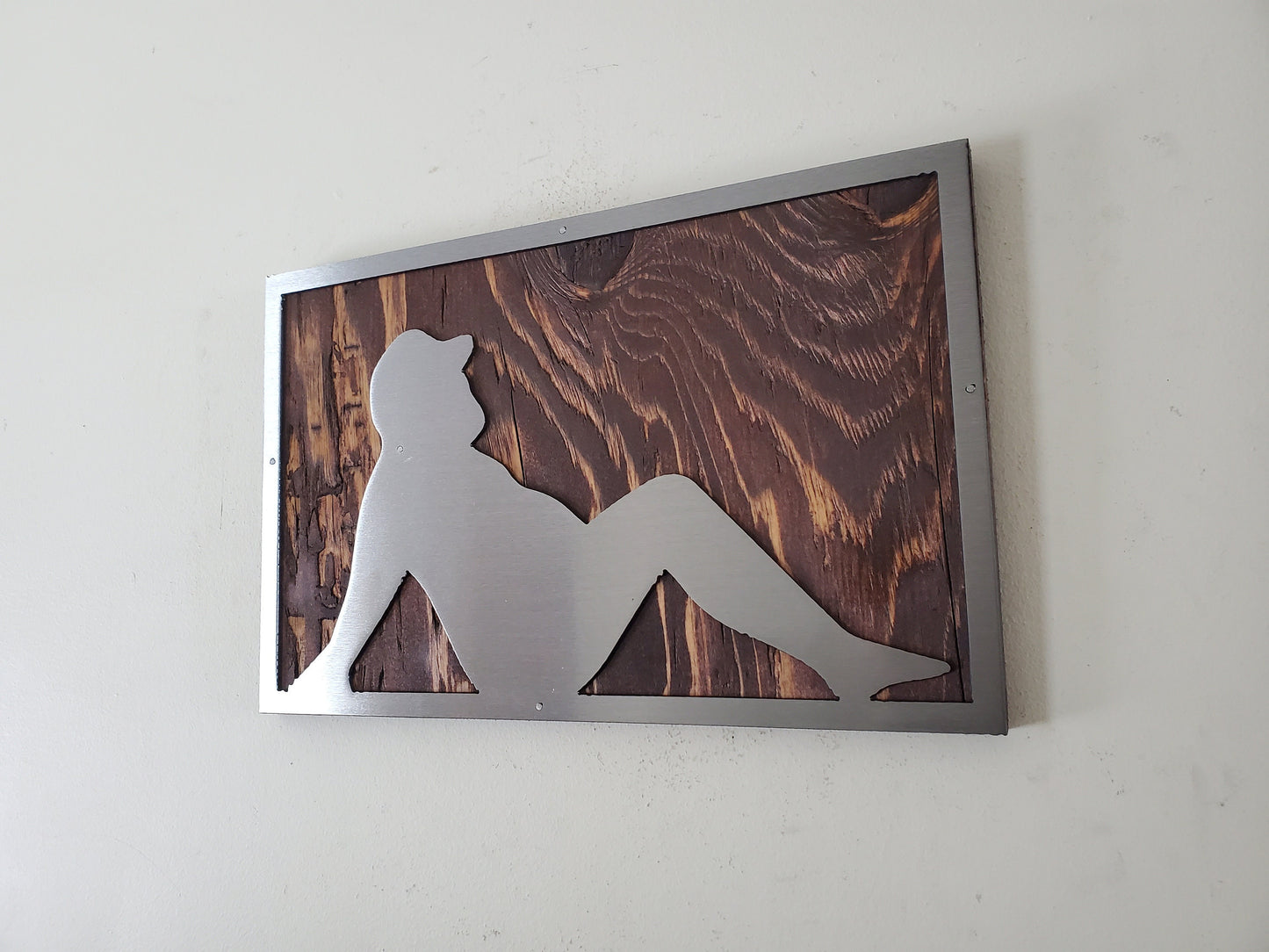 Metal cut-out sculpture of a Dad Bod physique, mounted on a rustic stained wood background, suitable for indoor display, easy to hang