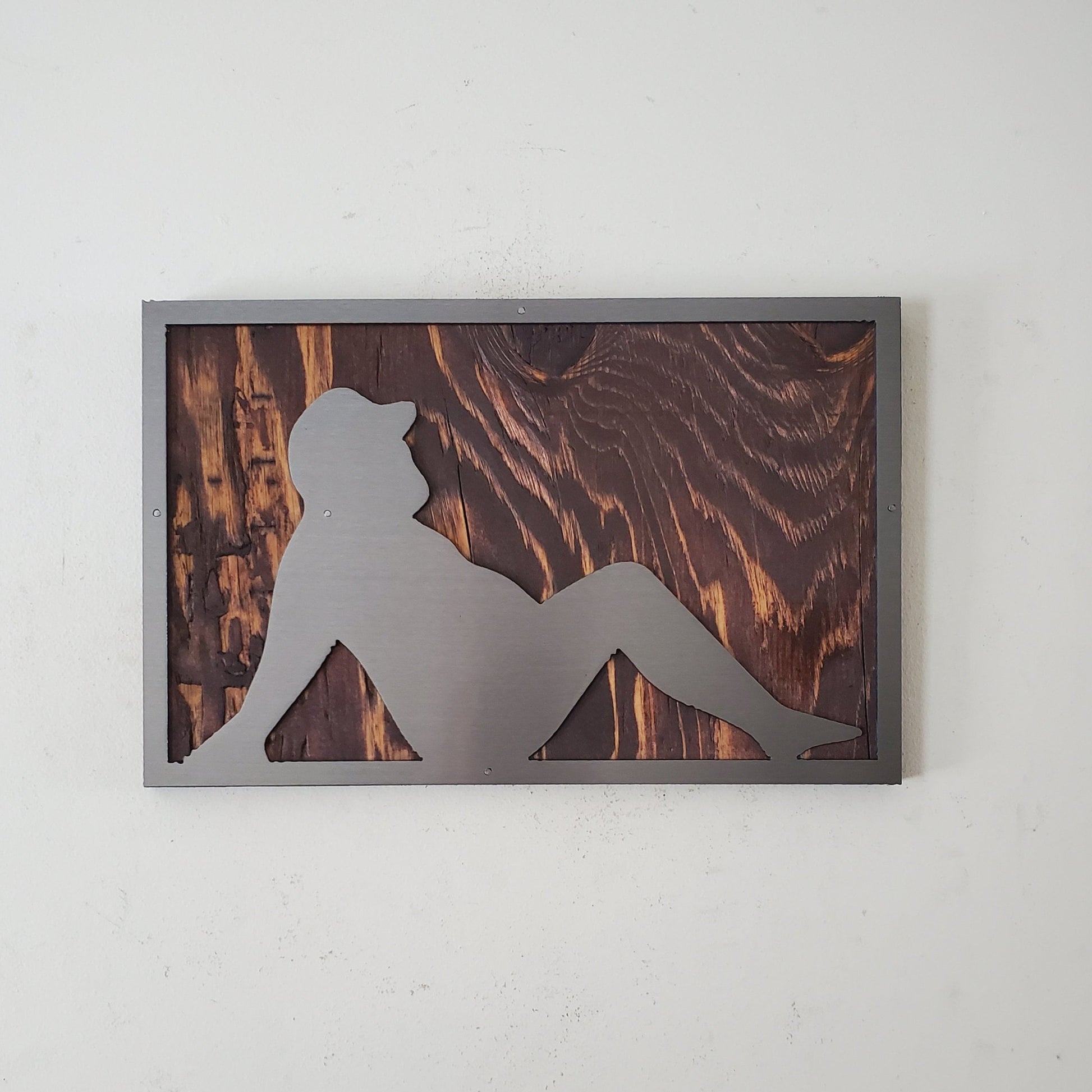 Metal cut-out sculpture of a Dad Bod physique, mounted on a rustic stained wood background, suitable for indoor display, easy to hang