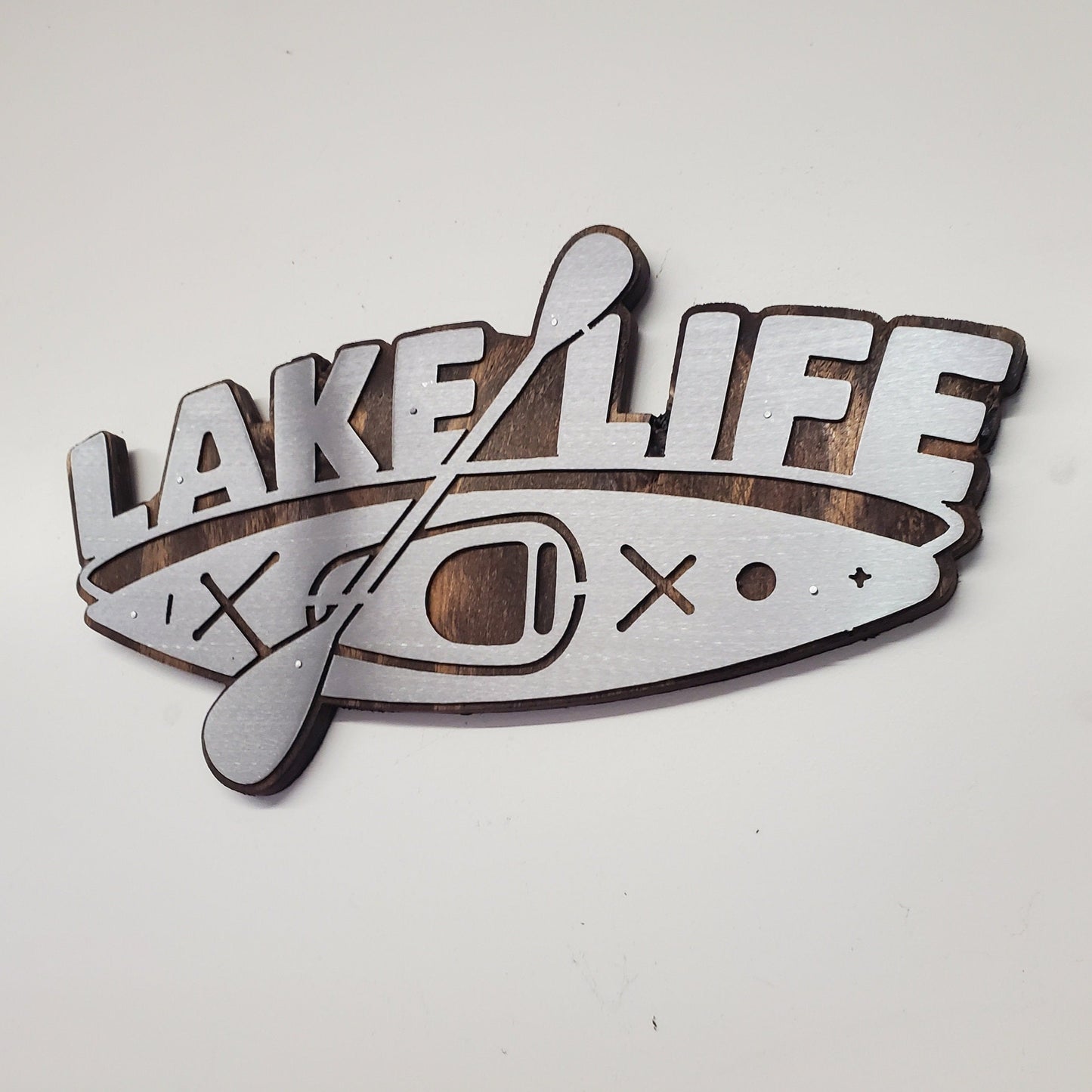 This is a Lake Life Kayak metal art wall decor on a stained wood background. This is the perfect wall decor for a lake home, cabin or office. Or a unique gift. This detailed metal cut out is attached to a stained wood back ground