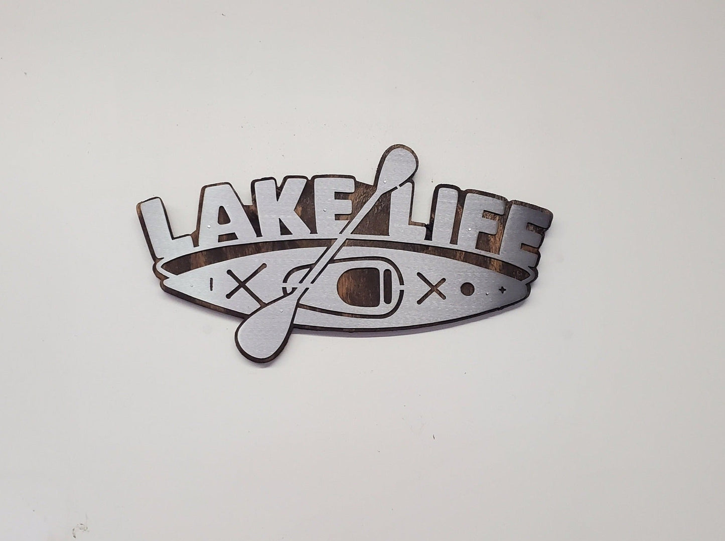 This is a Lake Life Kayak metal art wall decor on a stained wood background. This is the perfect wall decor for a lake home, cabin or office. Or a unique gift. This detailed metal cut out is attached to a stained wood back ground